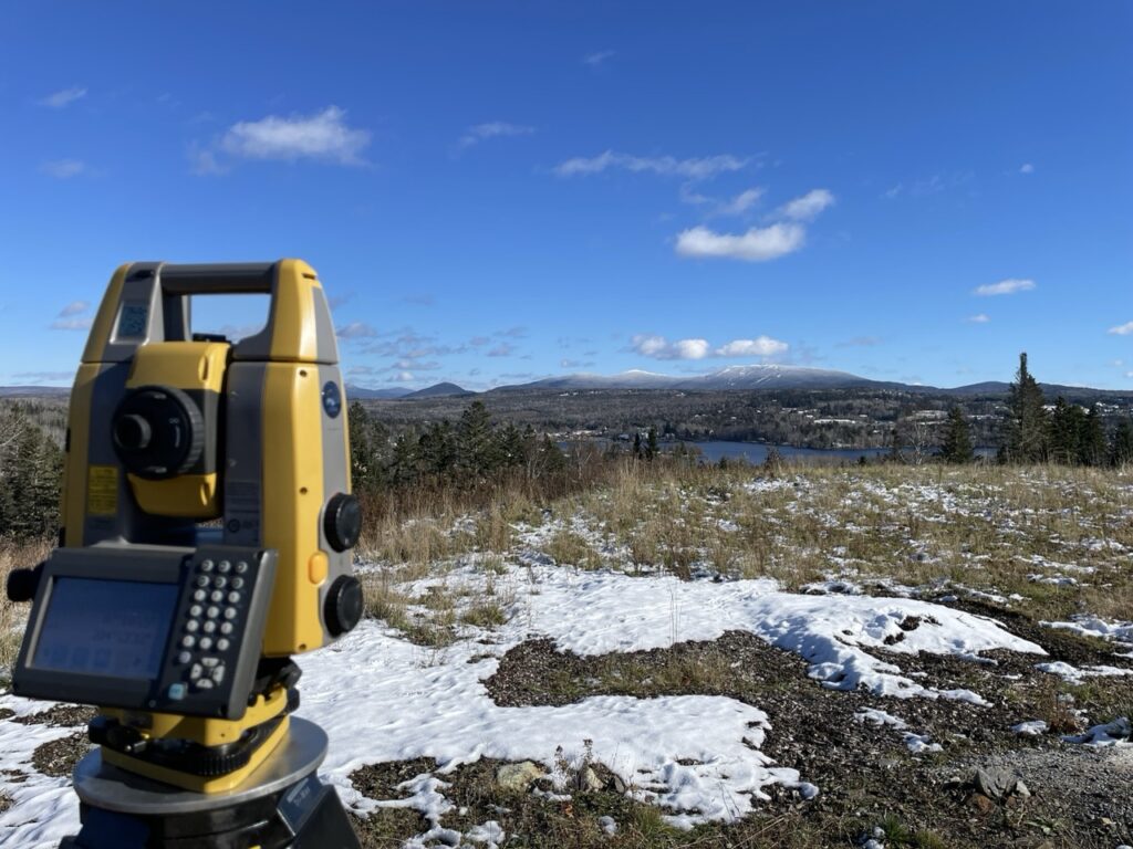 a photo of a Land surveying device and a mountain range in the background.