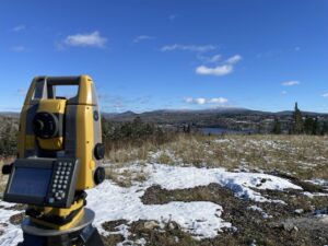 a photo of a Land surveying device and a mountain range in the background.